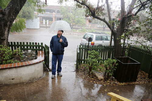 איש עומד בגשם בפתח ביתו